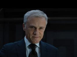 Christoph Waltz smirking with his gaze down to an unseen crowd.