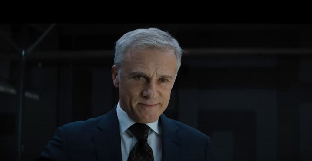Christoph Waltz smirking with his gaze down to an unseen crowd.