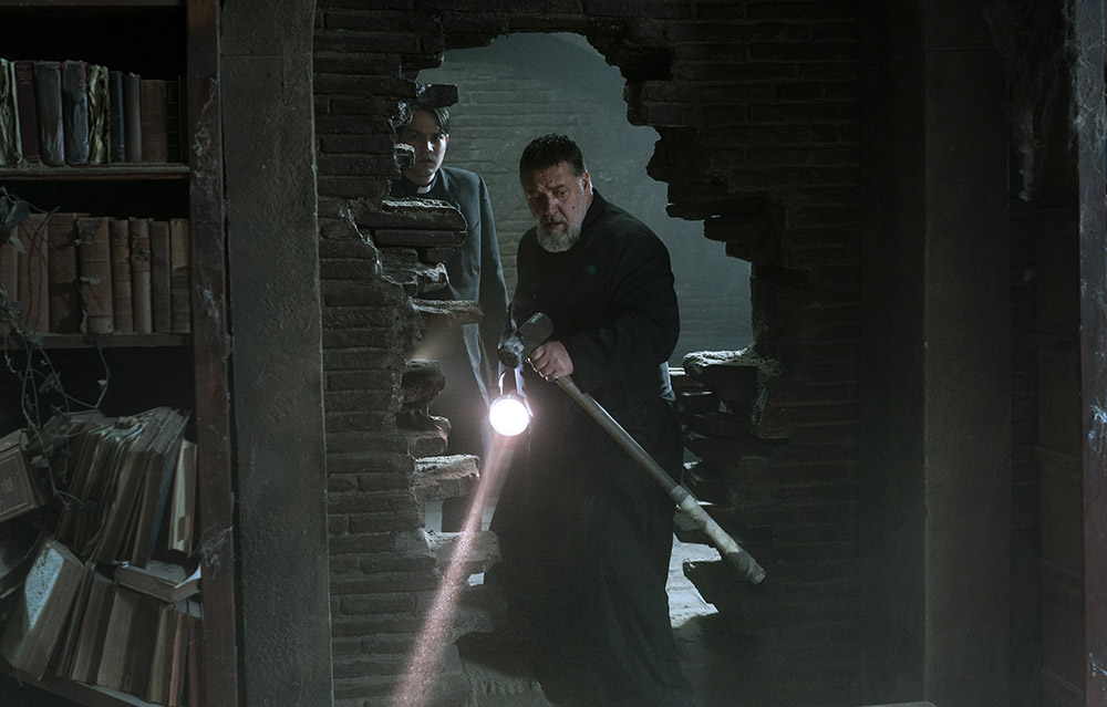 A priest shining a torch through a broken wall