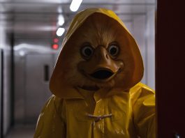 A human sized duck in a yellow raincoat roaming the corridors of a ship.