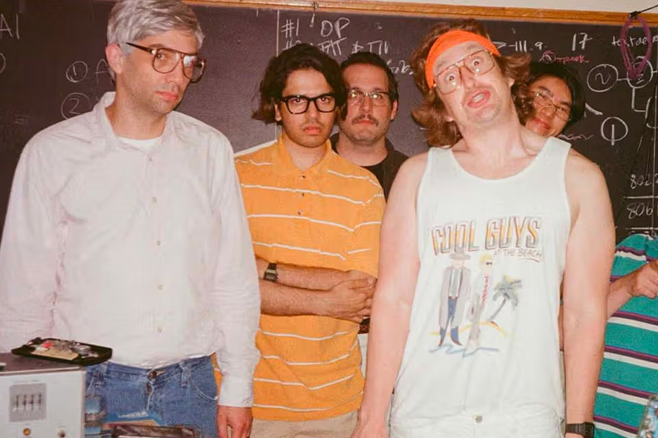 Four dudes in 90's clothes posing for a picture