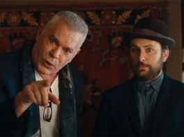 two men in a room, one looking clueless wearing a hat, the other angry pointing his finger