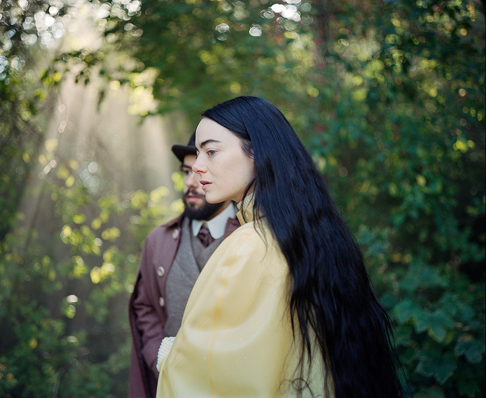 Side view of woman with long black hair and dressed in yellow in the forest.