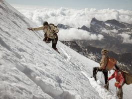Three people high up on a snowy mountain amongst the clouds