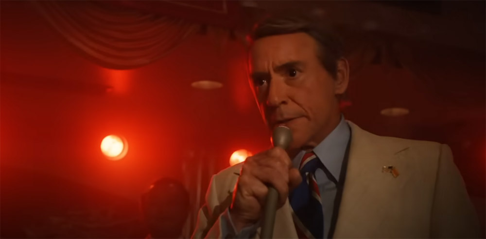 A man surrounded in a glow of red lights, in a microphone