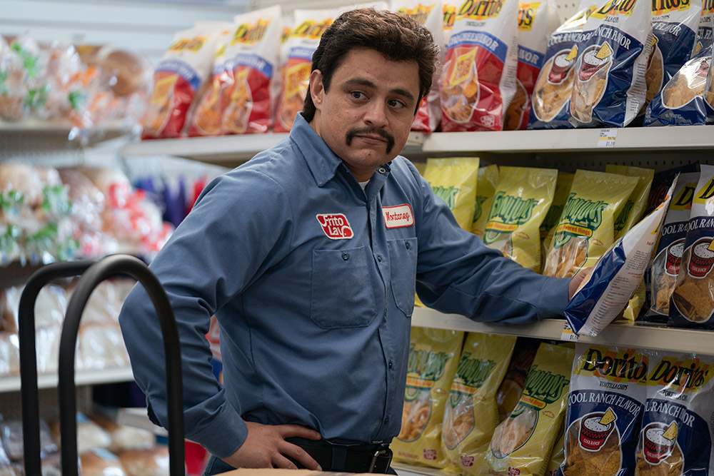 Mexican man standing in an American Food mart in front of chips