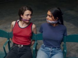 Two young girls tied up to chairs with gags in mouths looking at each other