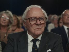 Old Man wearing glasses sitting in an audience - One Life