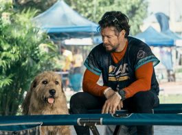Mark Wahlberg sitting next to a dog in Arthur The King