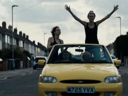 Women standing up in a moving yellow car in Silver Haze